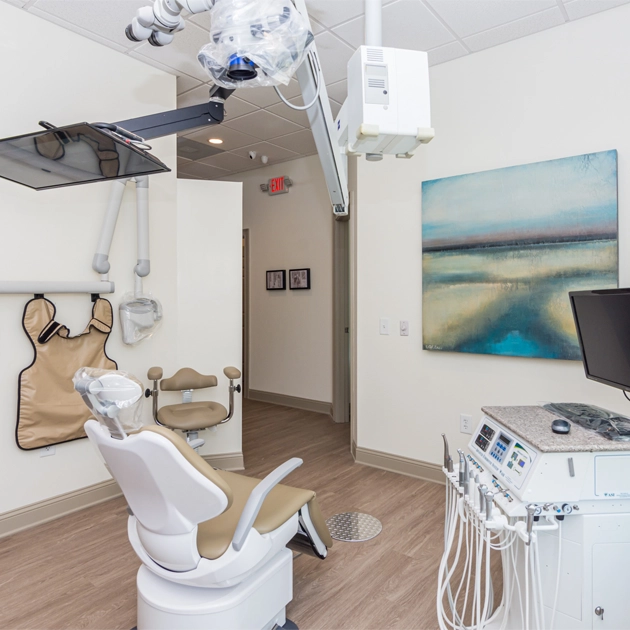 Modern dental operatory with chair, overhead light, equipment, and wall-mounted instruments in endodontic office.