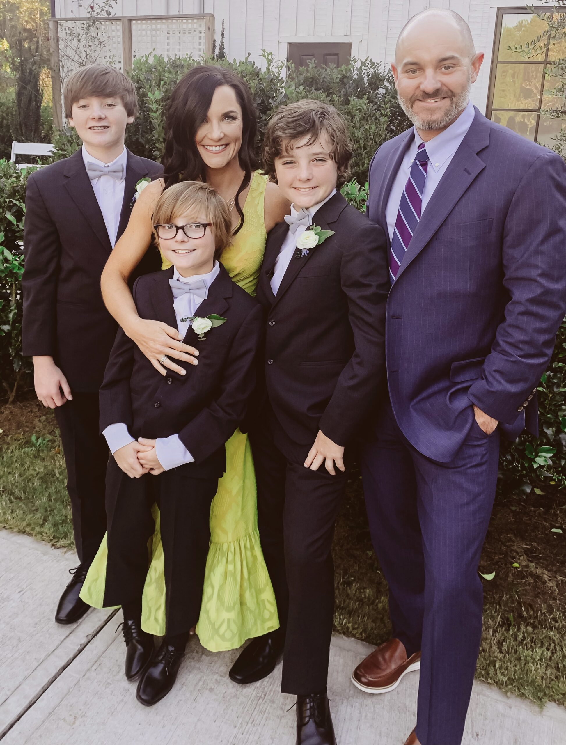 Family of five in formal attire posing outdoors against a building backdrop.